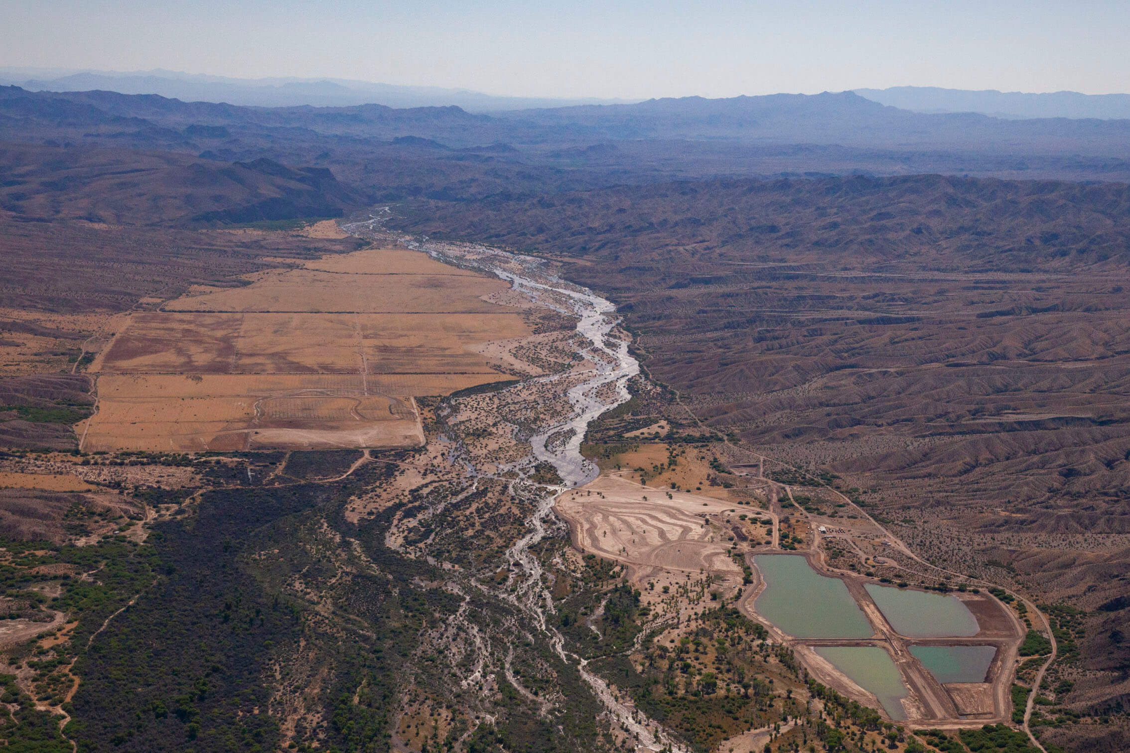 The Bill Williams River and floodplain during a time of high release from Alamo Dam. High flows in the Bill Williams are critical for renewing riparian forest and maintaining channel habitat. The river and its aquifer support conservation projects managed by federal and state partners, including ponds (lower right) for rearing native fish.